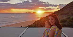 South African mom and travel blogger Janine visits Brenton on Sea. In this picture she is standing against the sunset with her little toddler.