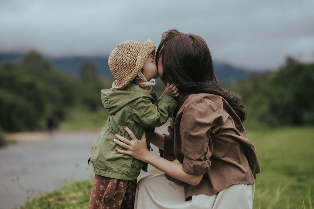 A woman getting a kiss from a toddler. Asian. 