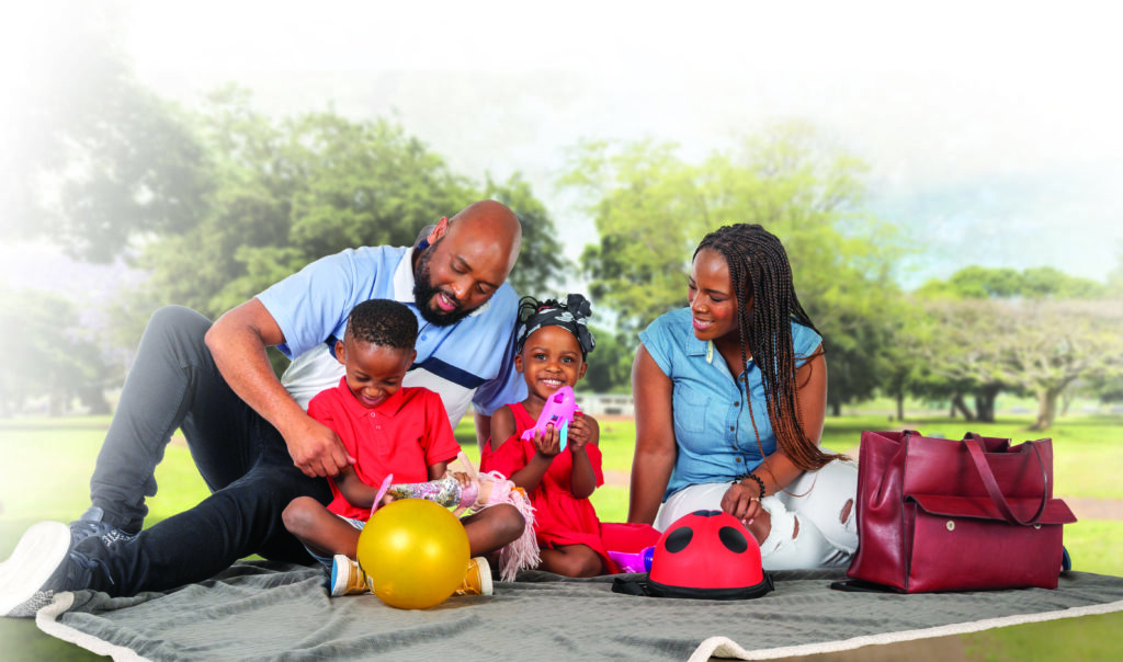 Family picnic scene, sitting on a blanket. with toys. 