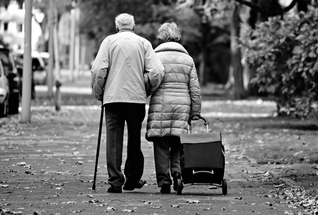 Elderly couple walking and the woman is dragging a shopping cart