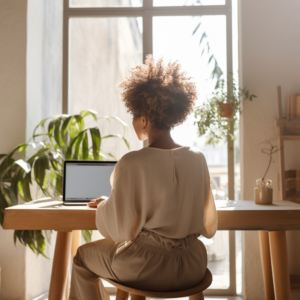 black woamn at her computer with lots of plants in the background