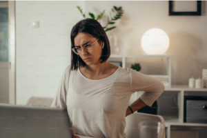 a woman sitting at a desk having back pain