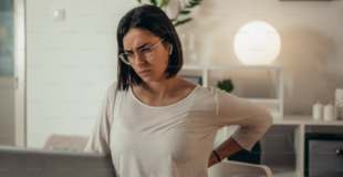 a woman sitting at a desk having back pain