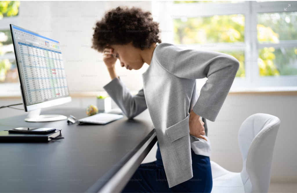 Woman sitting at a desk with backache. Having arch support improves your posture. 