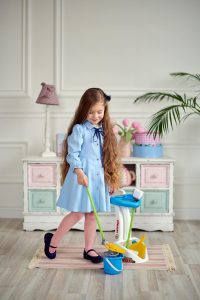 a girl cleaning with her toy mops and brooms