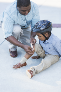 Dad helping his son with a hurt leg. Pain strikes unexpectedly and we need to be prepared.