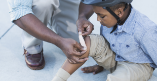 Dad helping his son with a hurt leg. Pain strikes unexpectedly and we need to be prepared.